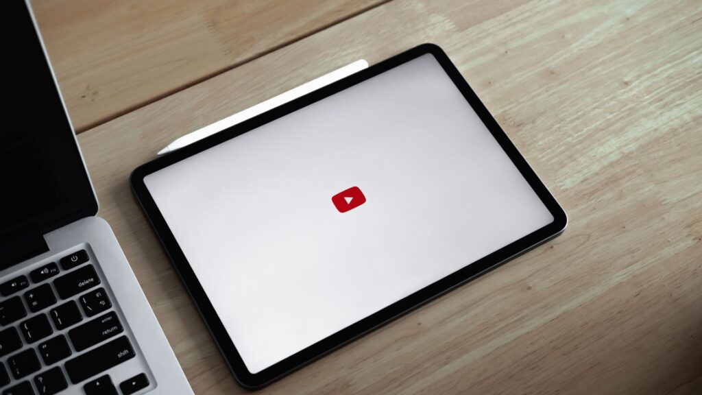 Tablet with YouTube icon on the screen next to a laptop.