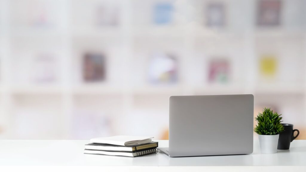 Laptop on office desk next to notepads.