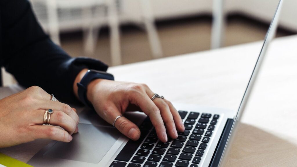 Person writing on laptop keyboard.
