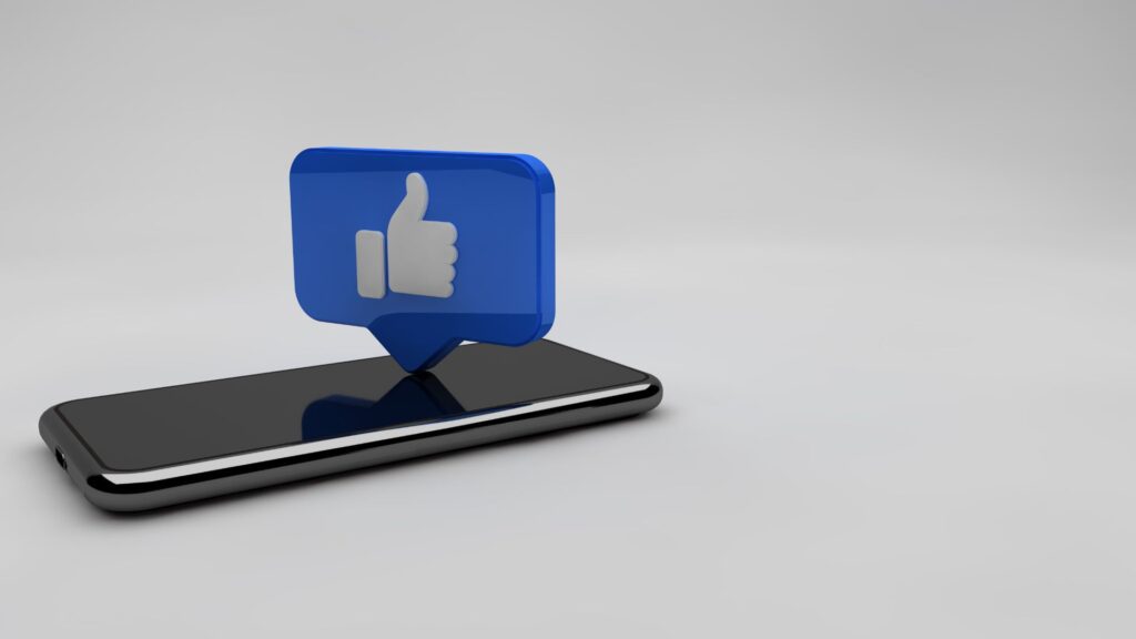 Facebook thumb symbol hovering over smartphone.
