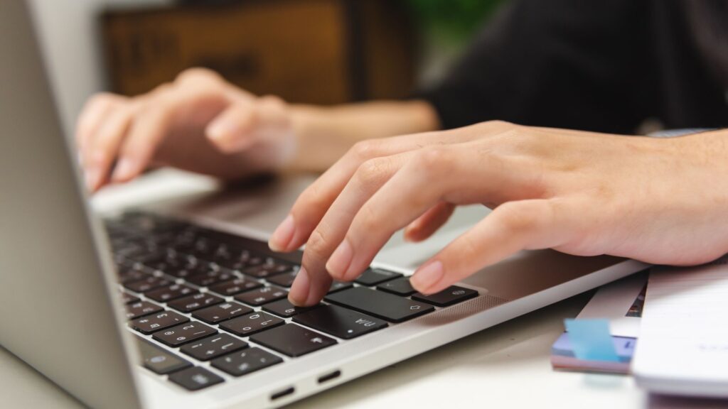 Hands typing on a laptop keyboard.
