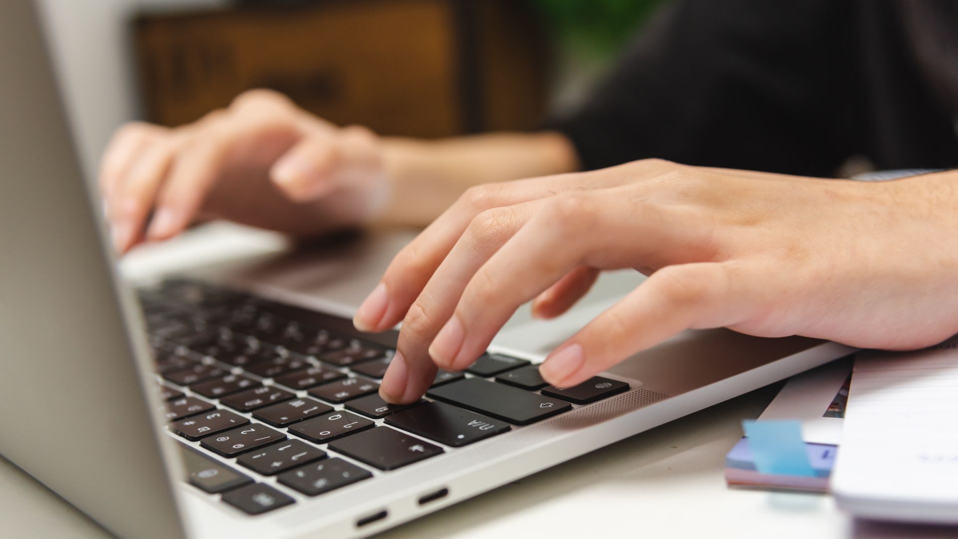 Hands typing on a laptop keyboard.