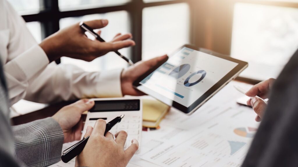 Persons analyzing market statistics on tablet.
