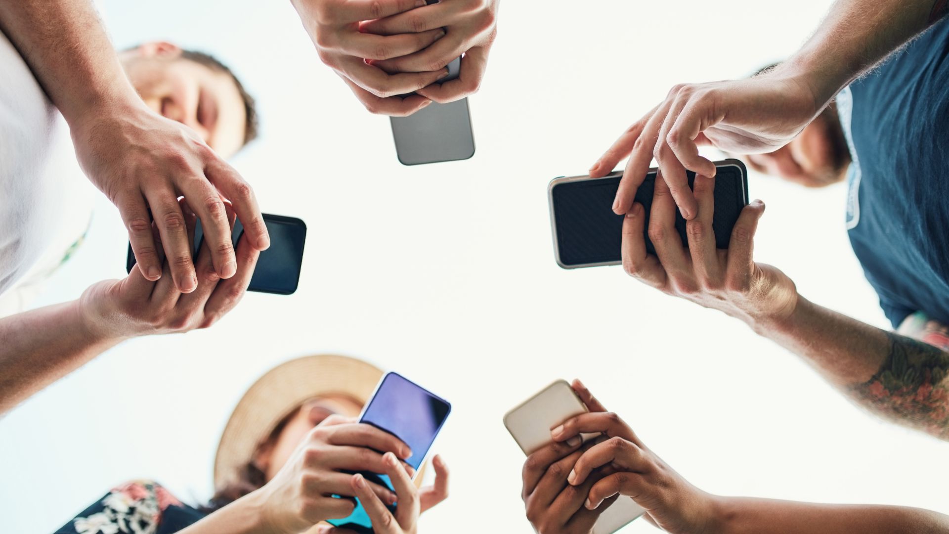 Persons standing in a circle watching viral content on their smartphones.